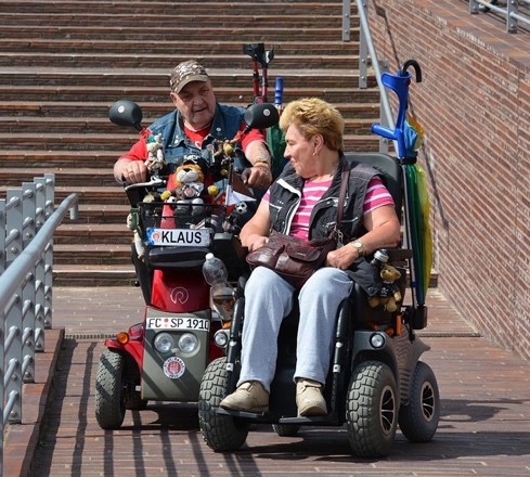A women and man in motorized wheel chairs wearing leather vests
